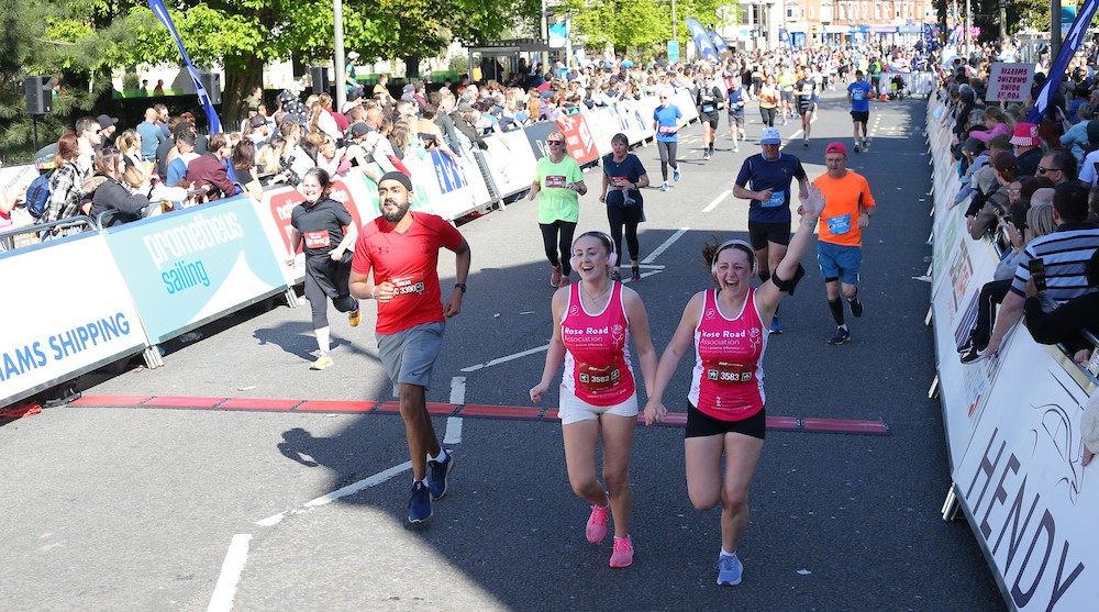 Two female runners holding hands as they cross the finish line