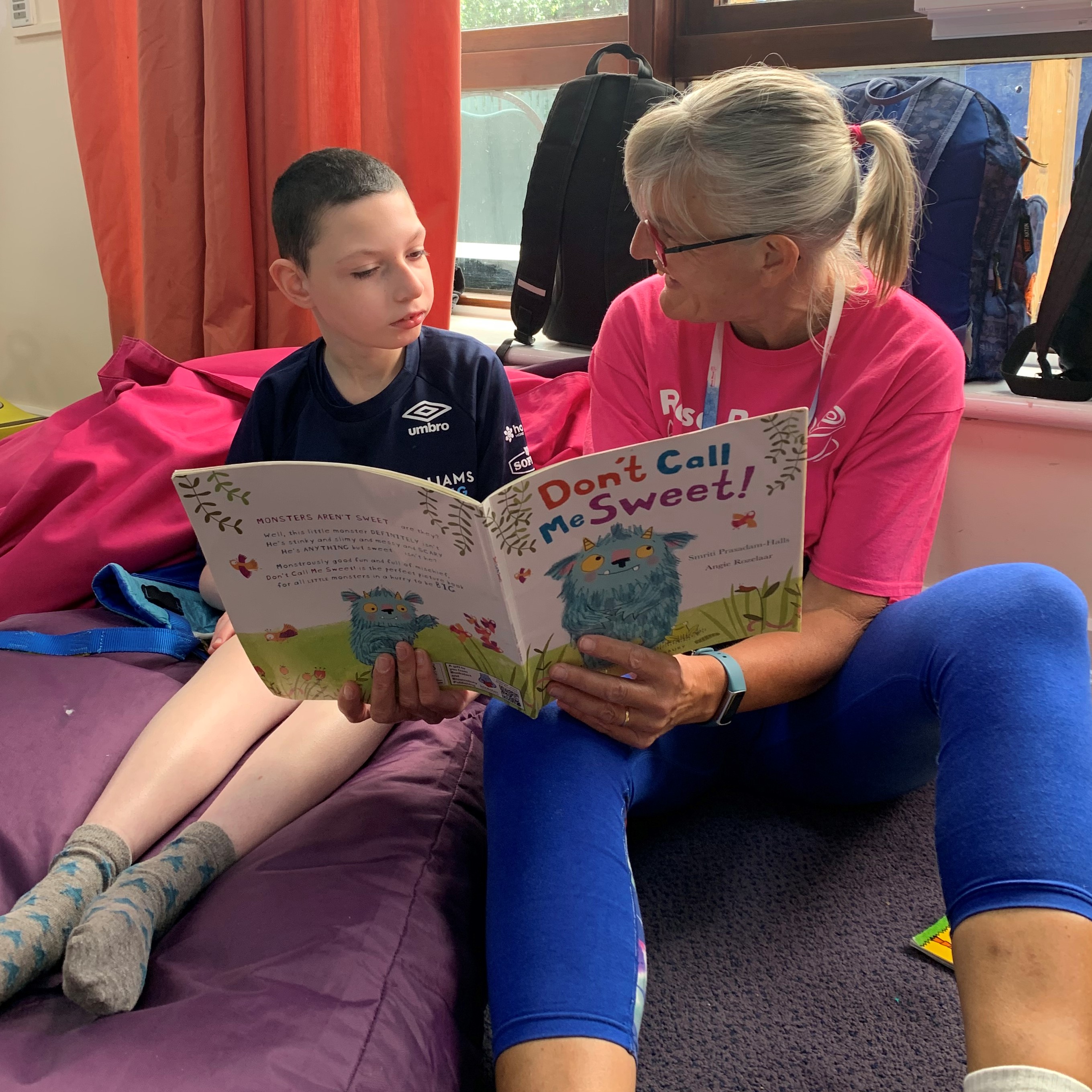 Young person with support worker reading a book